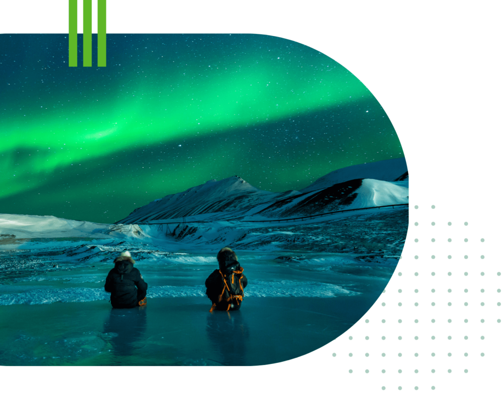 Photo of two people in a snowy landscape under the northern lights