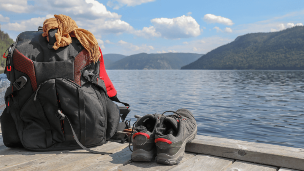 Sac à dos et chaussures de randonnée posés devant fjord du Saguenay